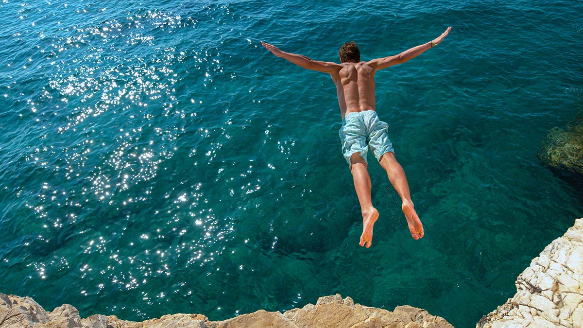 A man diving off a cliff as a metaphor for calculated risk-taking in small business.