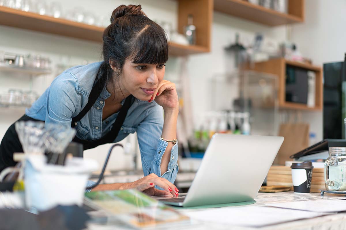 Small business owner researching SEO tips on a laptop in a shop environment