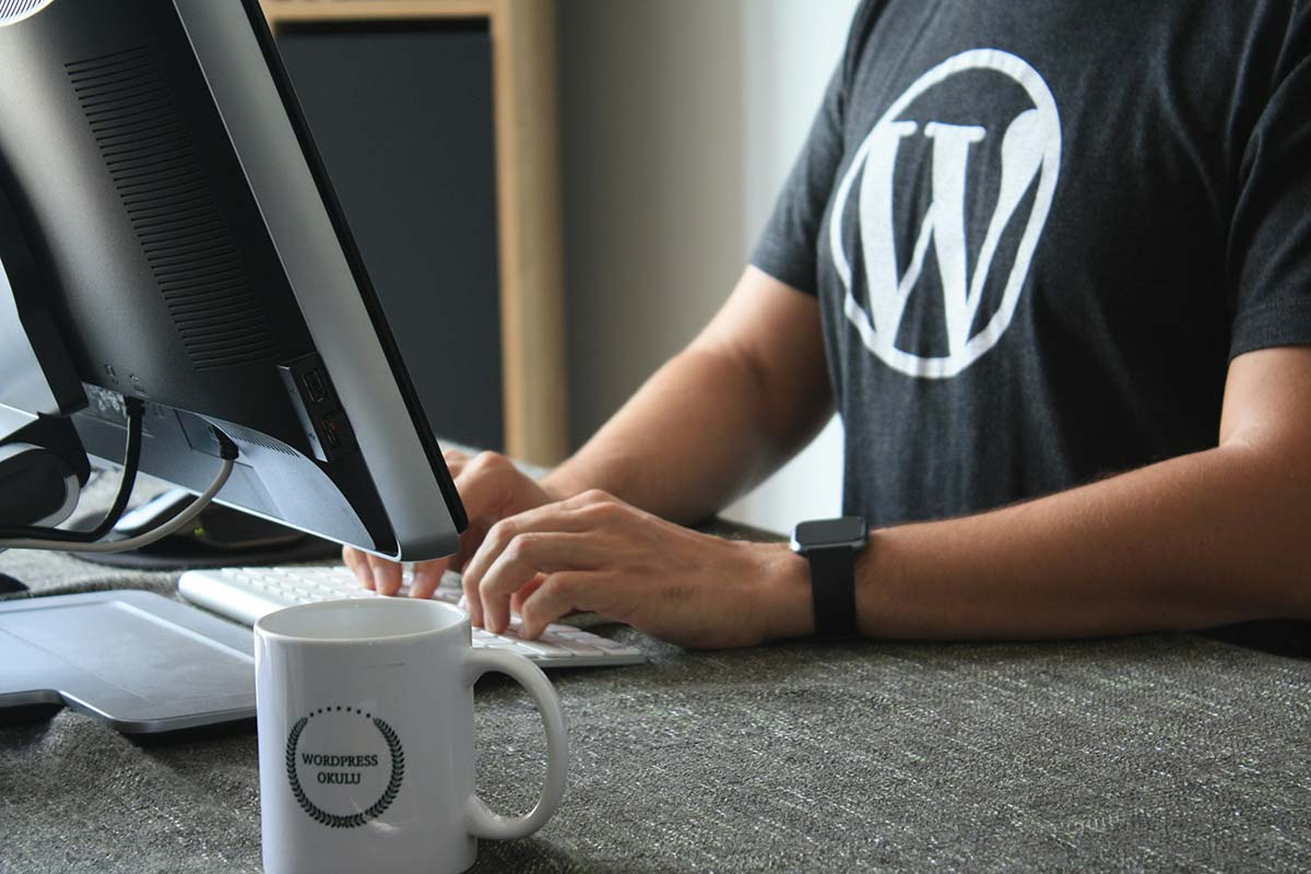 WordPress developer working at a desk with computer and coffee mug