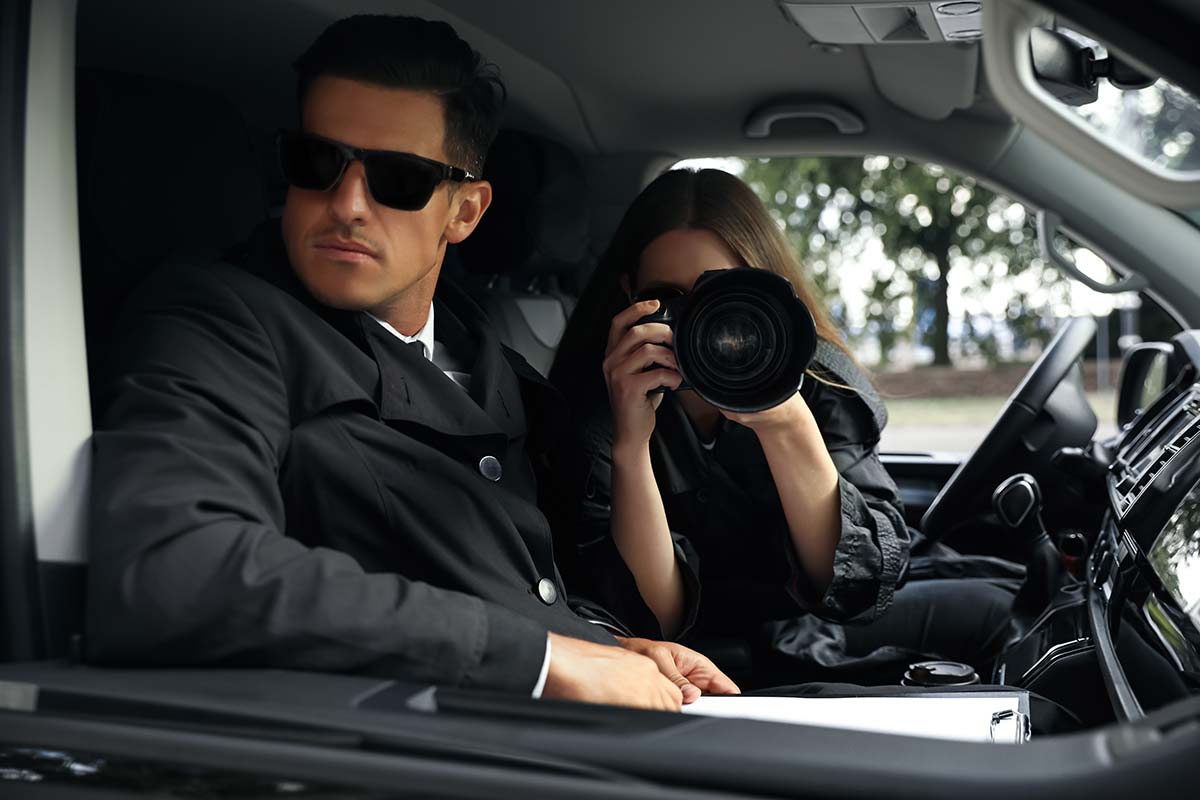 Two investigators in a car with camera, representing analyzing local competitors for WordPress SEO in Western Massachusetts