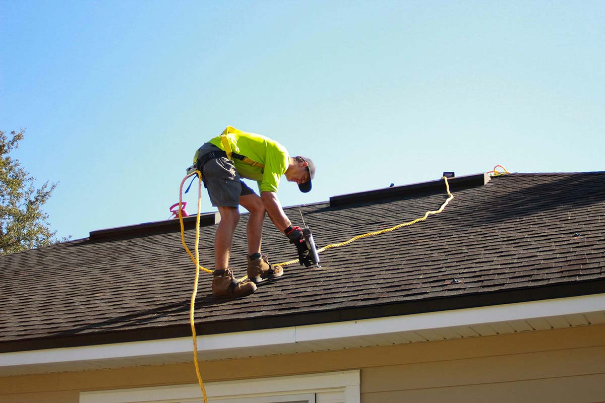 Roofer installing shingles on a residential home roof
