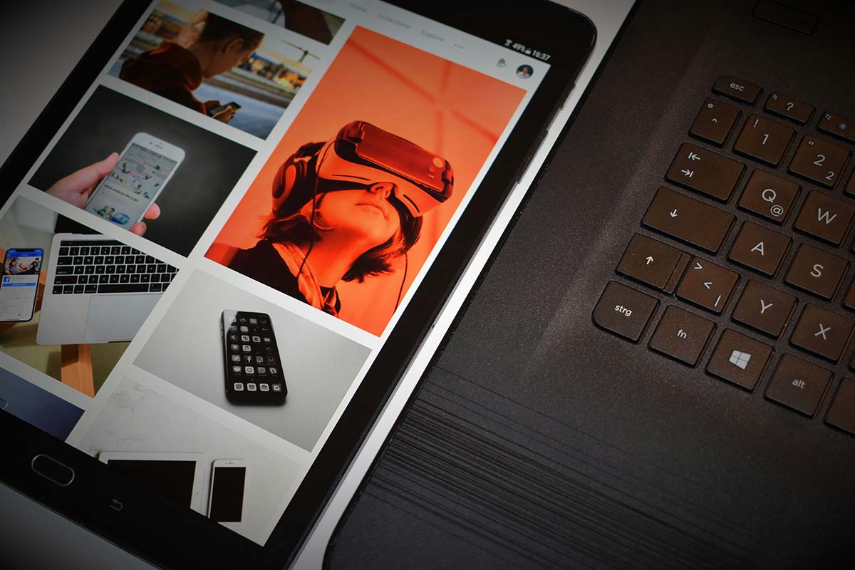 Tablet displaying modern app interface next to laptop keyboard, representing digital design and UX