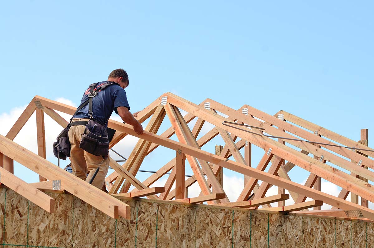 Construction worker installing roof trusses on a new home, representing contractors served by home services SEO.